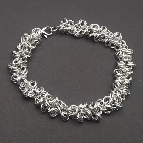 Bright silver aluminum chain mail bracelet on a dark grey background.