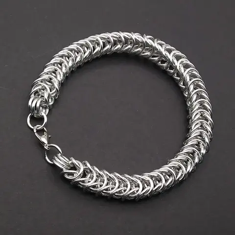 Bright silver aluminum chain mail bracelet on a dark grey background.