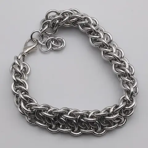 Silver chain mail bracelet laying on a white background