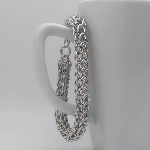 Silver chain mail bracelet hanging on a white mug.