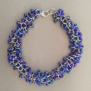 Bright silver aluminum chain mail bracelet with sapphire rainbow beads on a light grey background.