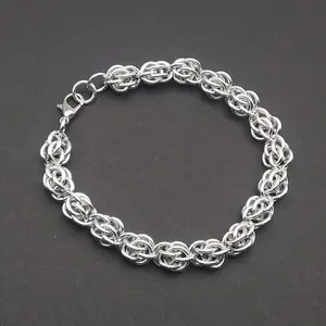 Bright silver aluminum chain mail bracelet on a dark grey background.