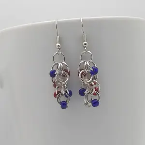 Bright silver aluminum chain mail earrings with USA mix beads on a white mug.