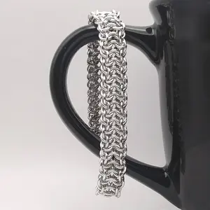 Bright silver aluminum chain mail bracelet on a black mug.