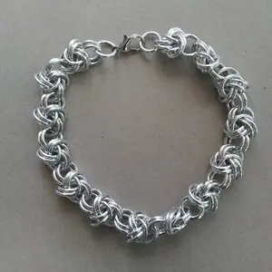 Bright silver aluminum chain mail bracelet on a grey background.