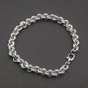 Bright silver aluminum chain mail bracelet on a dark grey background.