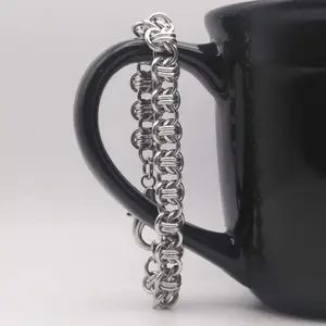 Bright silver aluminum chain mail bracelet on a black mug.