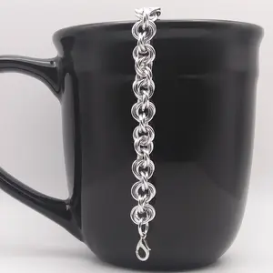 Bright silver aluminum chain mail bracelet on a black mug.