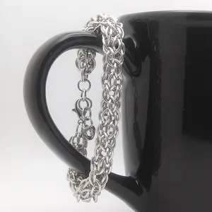 Bright silver aluminum chain mail bracelet on a black mug.